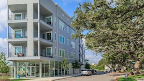 A multi-story residential building with balconies, large windows, and a glass storefront. - Cozy 1BR Apartment with Kitchen in Leander Tx. (Leander)