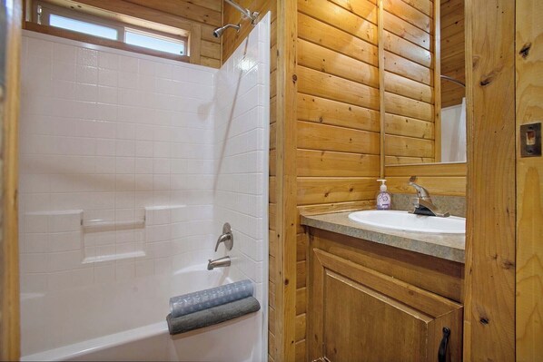 A wooden cabin bathroom with a bathtub, a sink, and a mirror. - Mendocino Redwoods RV Resort (Willits)