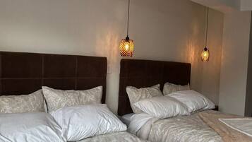 A hotel room with two beds, a dark headboard, and two hanging pendant lights.