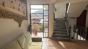 A spacious living area with a sofa, a staircase, and a large window offering a view of the cityscape. - JUAN PLACIDO Hospedaje (Cusco)