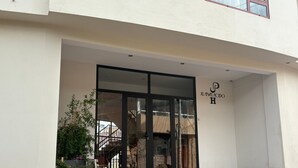 A building entrance with a glass door, steps, and a logo on the wall. - JUAN PLACIDO Hospedaje (Cusco)