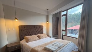 A bedroom with a large bed, two bedside tables, a wardrobe, and a window with curtains. - JUAN PLACIDO Hospedaje (Cusco)
