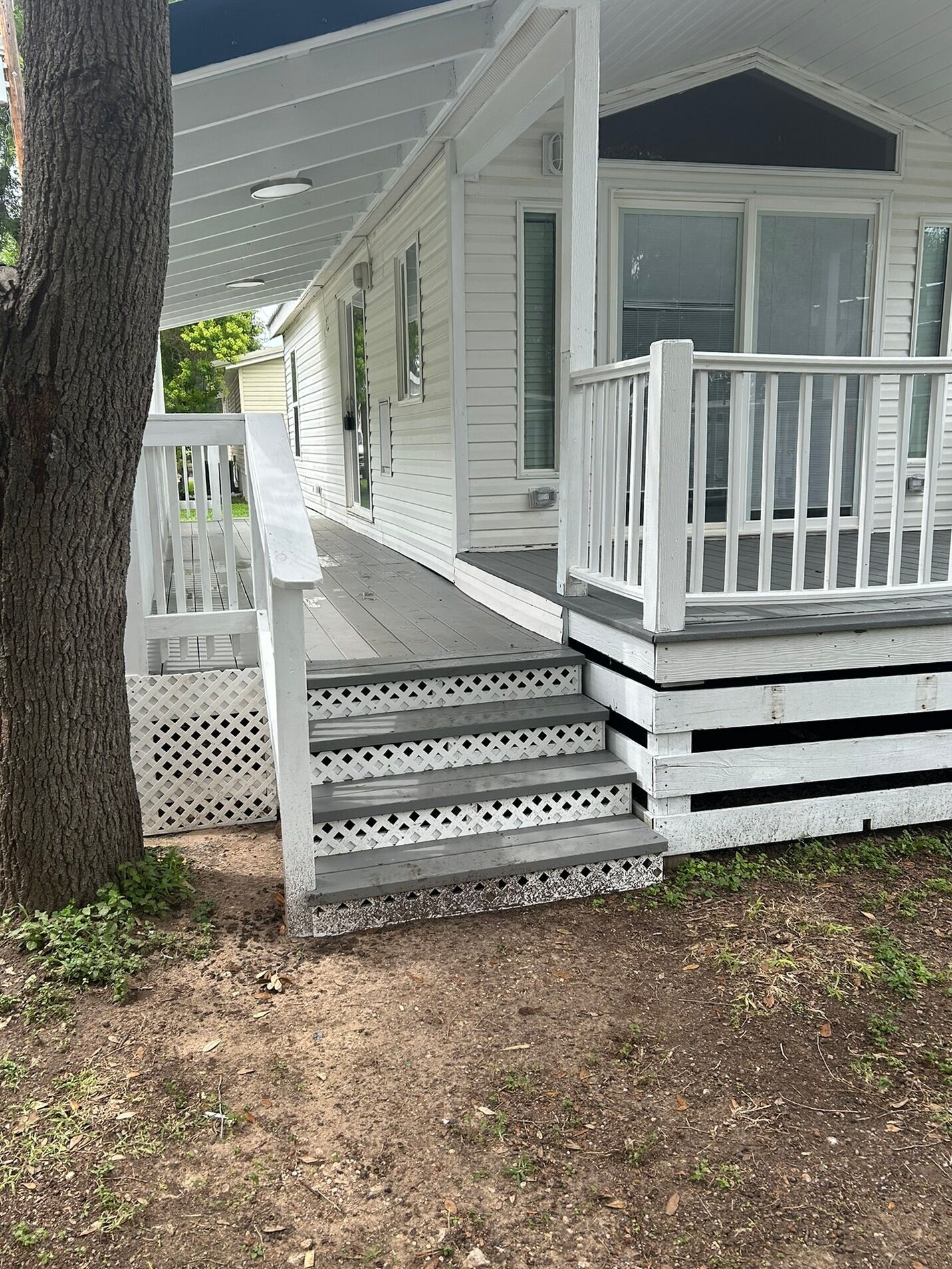 A white wooden house with a porch, steps, and a railing.