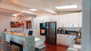 A modern kitchen with white cabinets, stainless steel appliances, and a marble island with bar stools. - Eria events and stay on Paradise, premier modern waterfront retreat (Corte Madera)