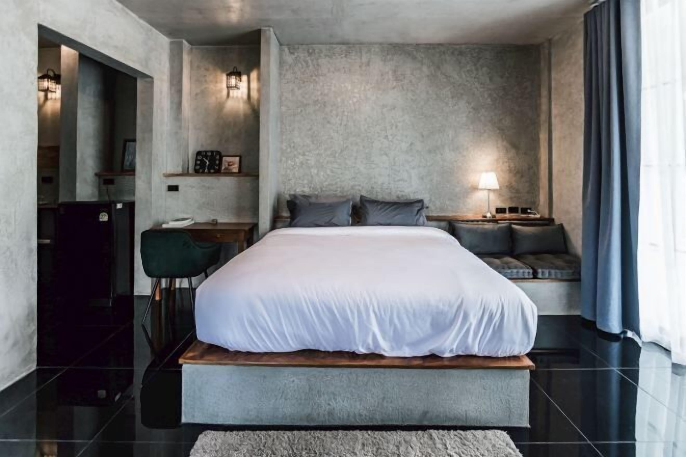 Un dormitorio moderno con una cama grande, una mesita de noche, una silla y un escritorio.