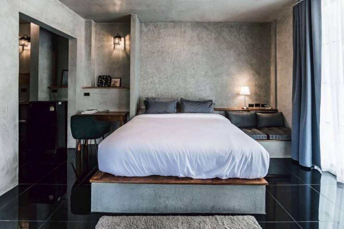 Une chambre moderne avec un grand lit, une table de chevet, une chaise et un bureau.