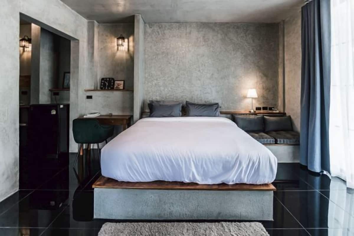 Un dormitorio moderno con una cama grande, una mesita de noche, una silla y un escritorio.