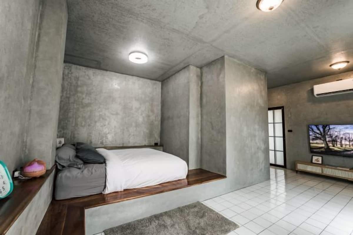 Un dormitorio con cama, televisor y ventana.