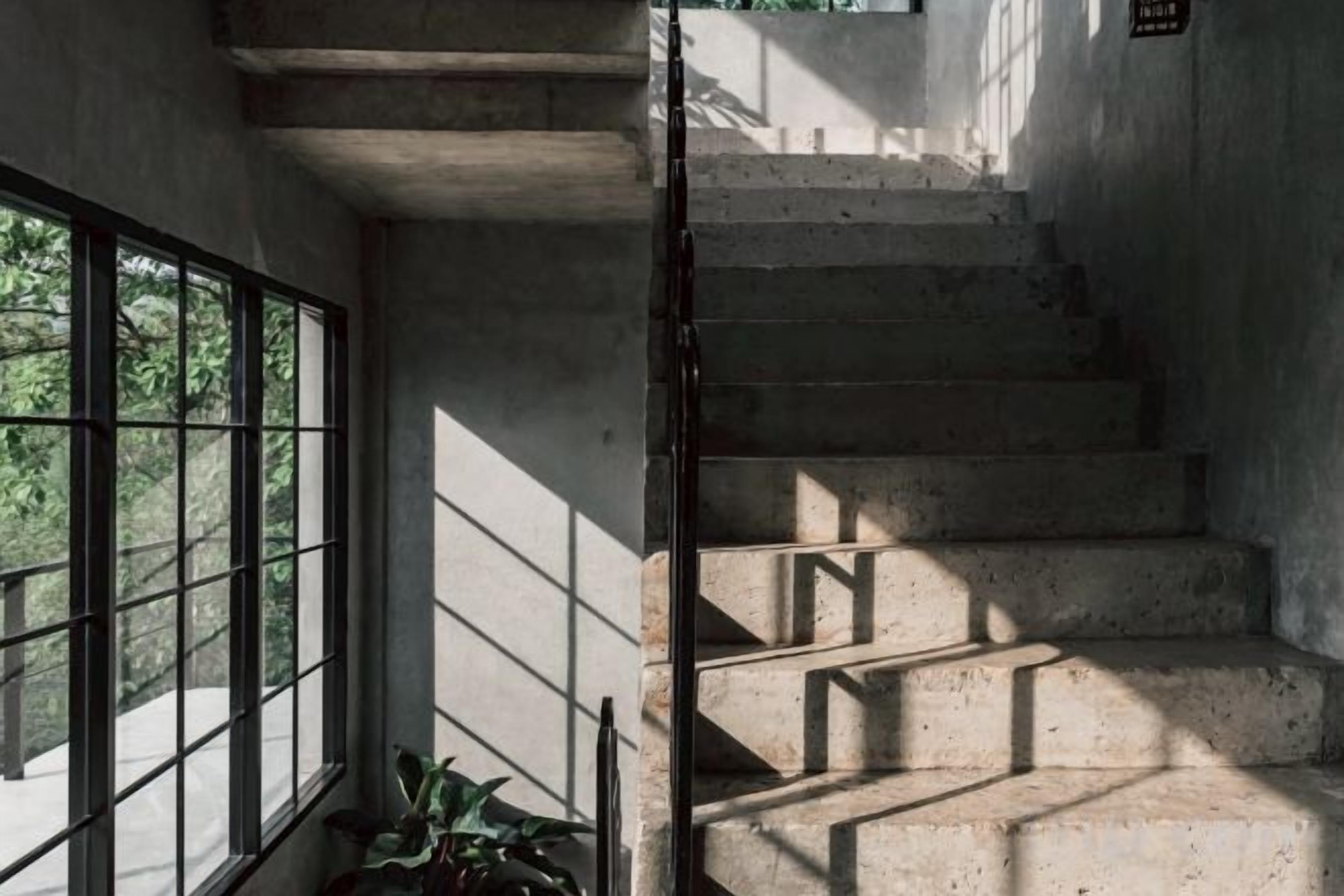A concrete staircase with a metal railing, leading to an upper level.