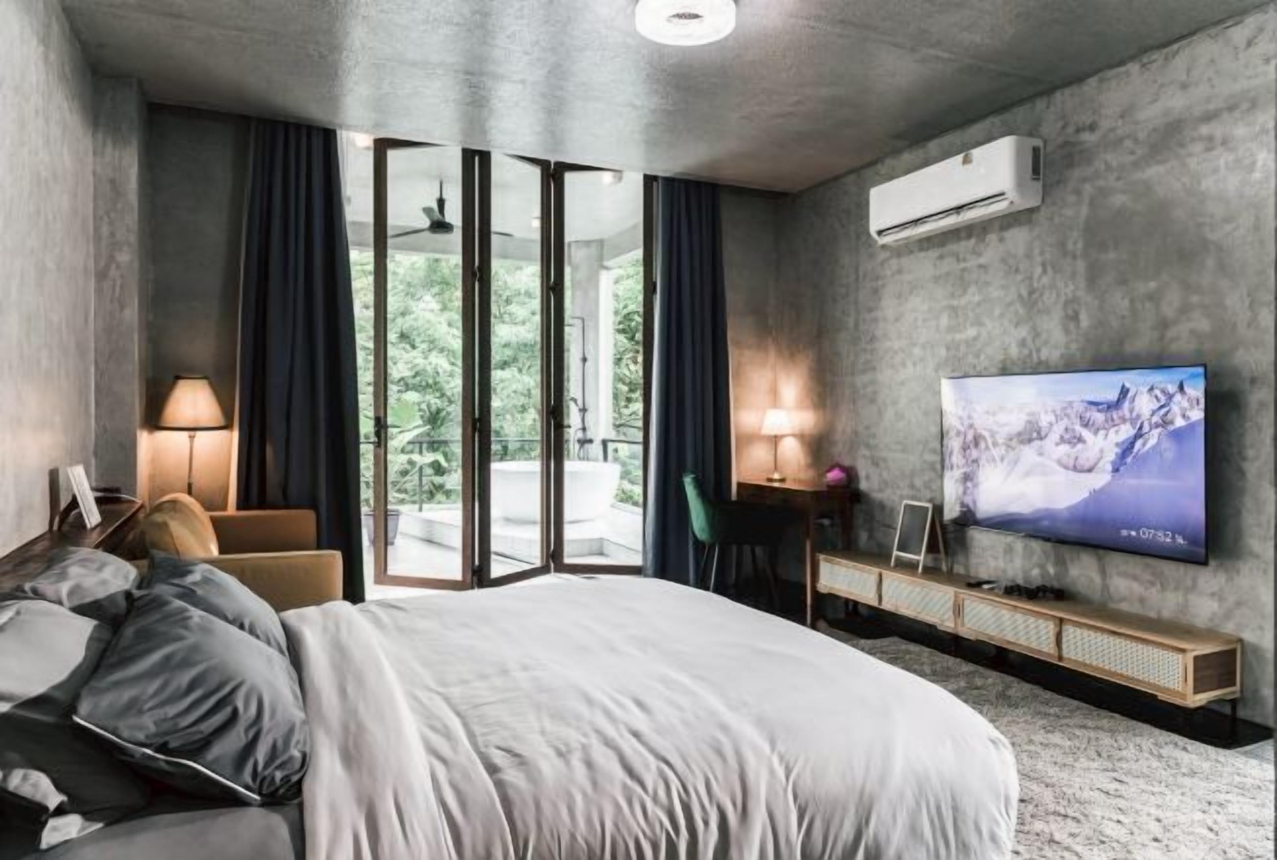 Una habitación de hotel moderna con una cama grande, un televisor en la pared y un balcón con cortinas.