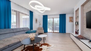 Een moderne woonkamer met een grijze bank, een ronde salontafel en een kleden van koeienhuid.