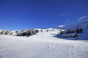 A snow-covered ski slope with a lodge and trees in the background. - Luxescape-Chalet Apartement Almzeit-Wandern-Traumaussicht-Sauna-Naturschutzgebiet (Predlitz-Turrach)