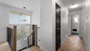 A modern interior with a staircase, a glass door, and a hallway leading to a bathroom. - 4-bedroom house in delightful Longueuil with AC, bar and karaoke (Longueuil)