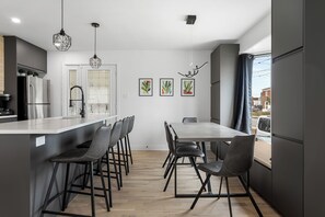 Eine moderne Küche mit Kochinsel, Barhocker und einem Esstisch mit Stühlen.