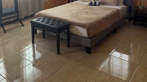 Une chambre d’hôtel comprenant un lit, des tables de chevet, un ventilateur de plafond, un appareil de climatisation, des rideaux et une fenêtre.