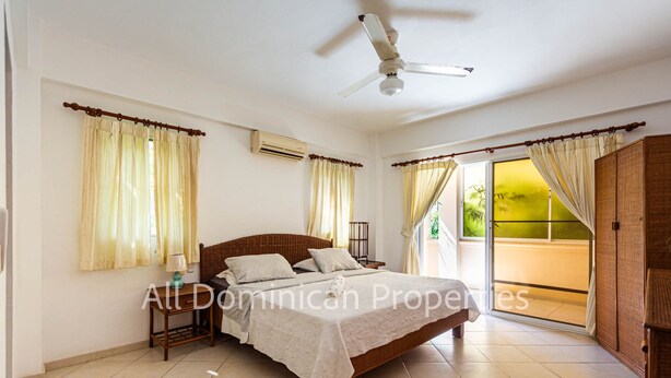 Ein Schlafzimmer mit Bett, Vorhängen, Deckenventilator und Blick ins Freie.