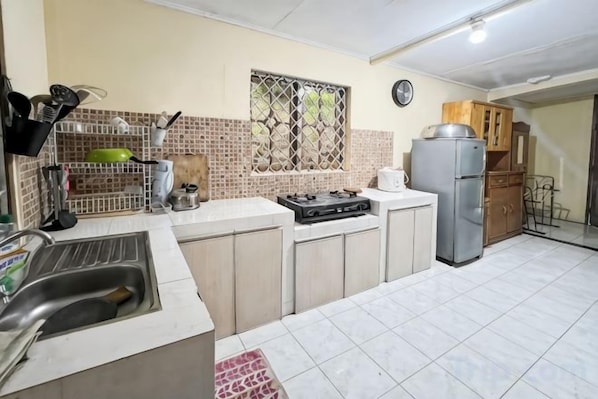 A kitchen with a sink, stove, refrigerator, and cabinets.