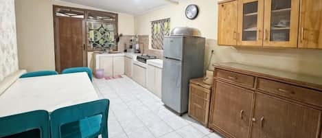 A kitchen with a refrigerator, wooden cabinets, and a dining table with chairs.