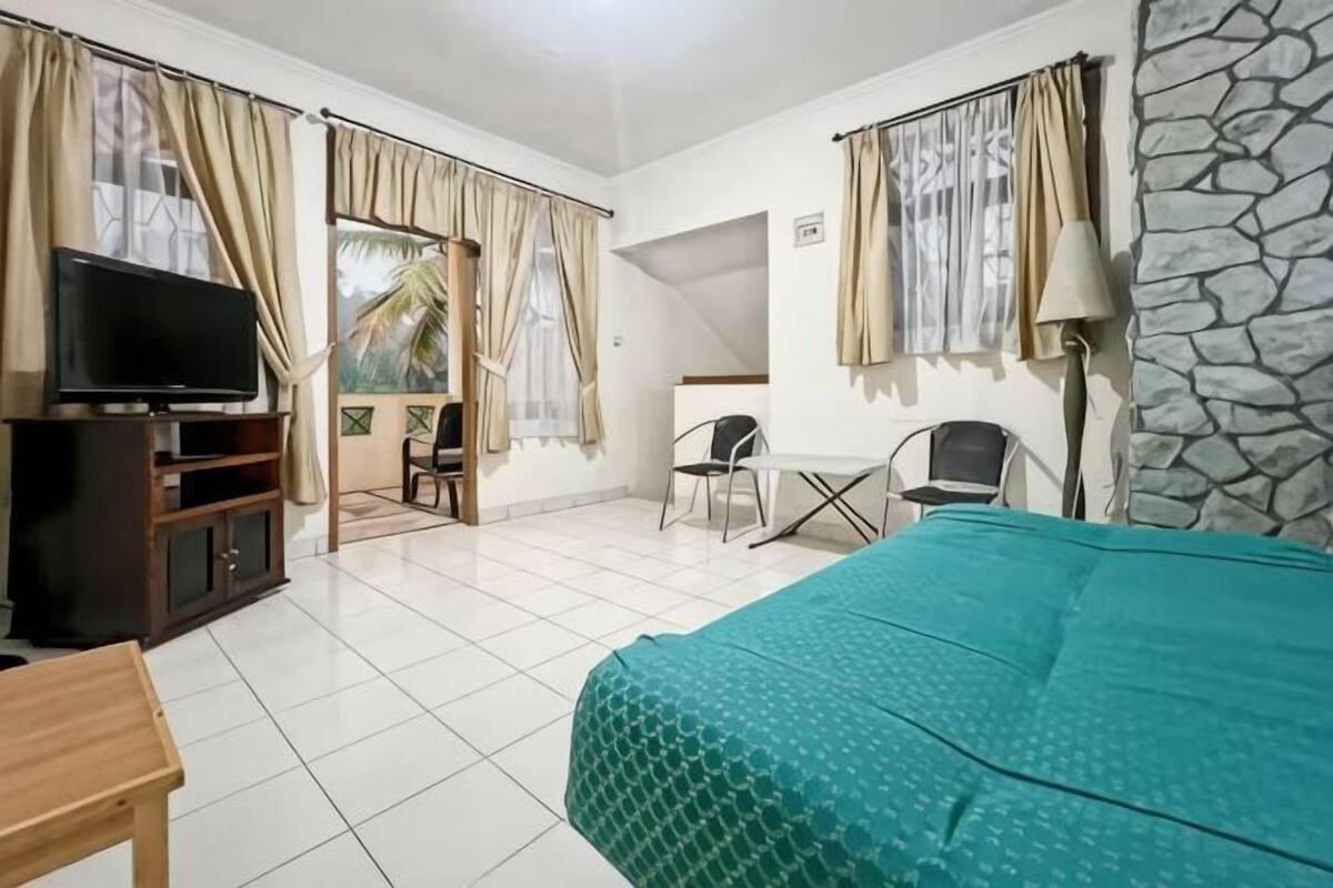 Una habitación de hotel con cama, televisión, escritorio y silla.