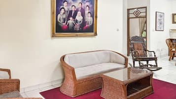 Una sala de estar con un sofá de mimbre, una mesa de centro de vidrio y un tapete rojo.