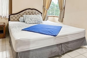 Un lit bien fait, avec un matelas blanc, une housse de lit grise et une couverture bleue.