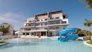 Een hotel met een zwembad, een glijbaan en een bord waarop 'ZENSES' staat.