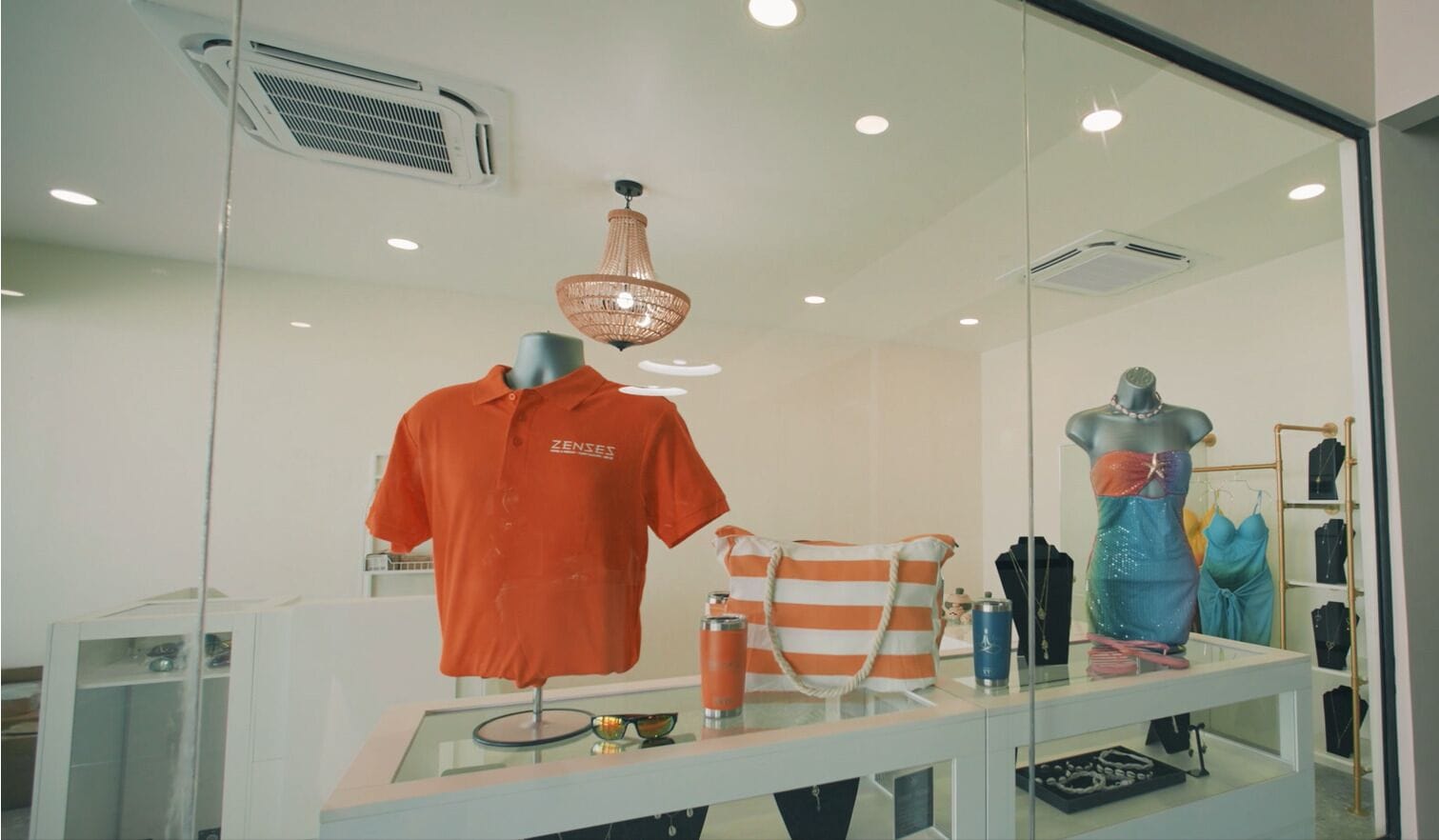 Een etalage met een pop in een oranje shirt, een gestreepte tas en een blauwe jurk.