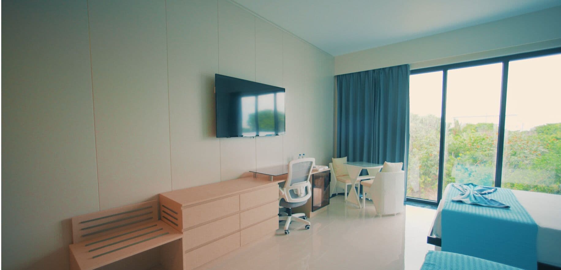 Une chambre d’hôtel équipée d’un bureau, d’une chaise et d’une grande fenêtre avec des rideaux.