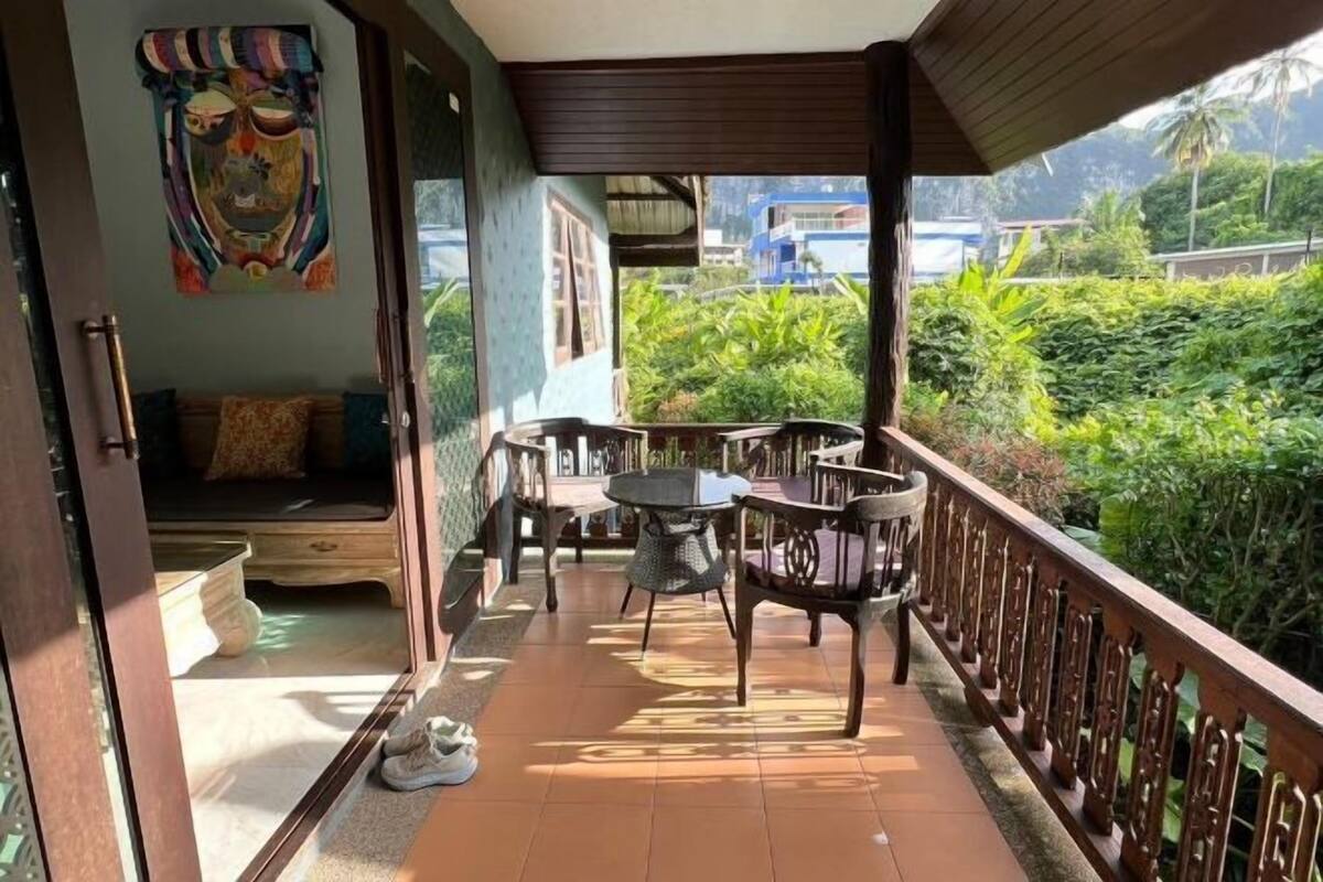 A covered balcony with a table and chairs, a sofa, and a decorative wall piece.