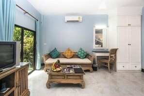 A living room with a sofa, coffee table, TV, and a wardrobe. - Moubillow Resort (Krabi)