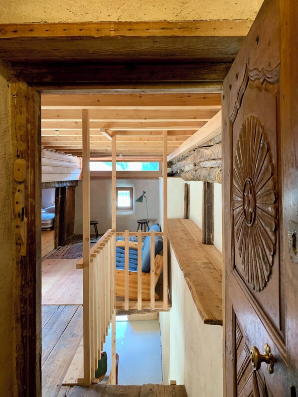 A wooden interior with a bed, a desk, and a window.