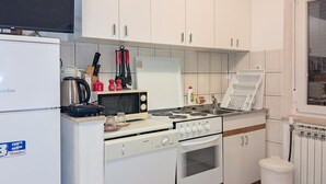Eine kompakte Küche mit weißen Schränken, einem Herd, einer Mikrowelle und einem Kühlschrank.