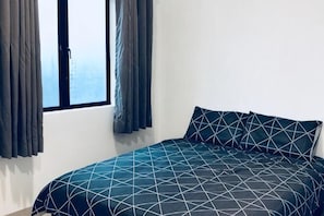A bed with a geometric-patterned bedspread, a window with curtains, and a plain wall. - LunaStay (Shared Common Area) (Sungai Seluang)