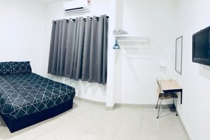 A bedroom with a bed, a desk, a chair, a TV, and a window with curtains. - LunaStay (Shared Common Area) (Sungai Seluang)