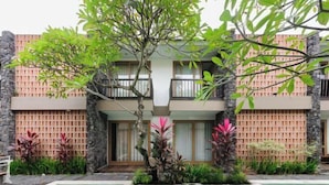 A two-story building with a pool, surrounded by plants and a wooden fence. - Sans Vibes Astana Residence Seminyak (Bali)
