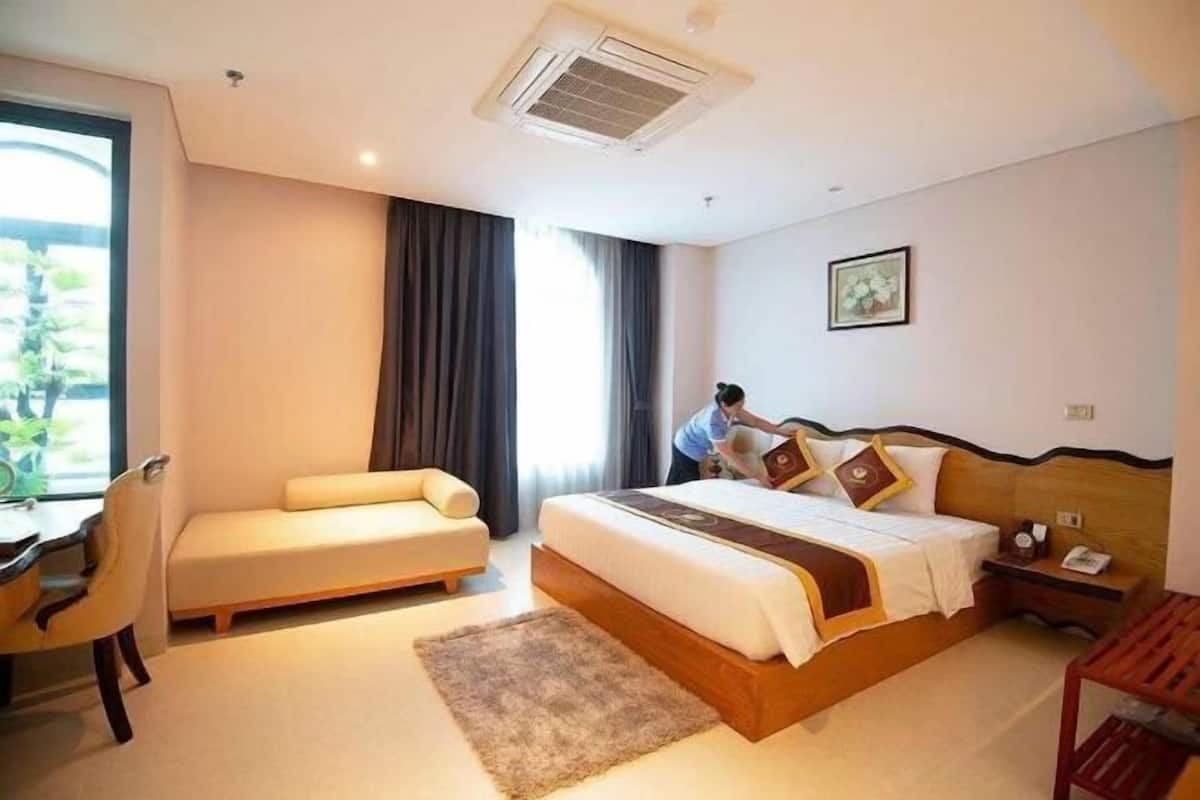 A hotel room with a bed, a sofa, a desk, and a window.