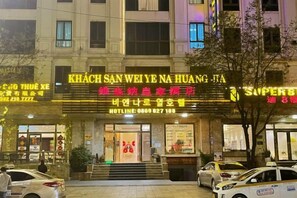 A hotel with a prominent sign in multiple languages, a visible entrance, and a parking area with cars. - Vienna Royal Hotel Bac Ninh (Bac Ninh)