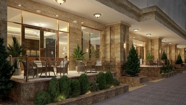 Esterno di un hotel con posti a sedere all'aperto, fioriere in pietra e un ingresso ben illuminato.