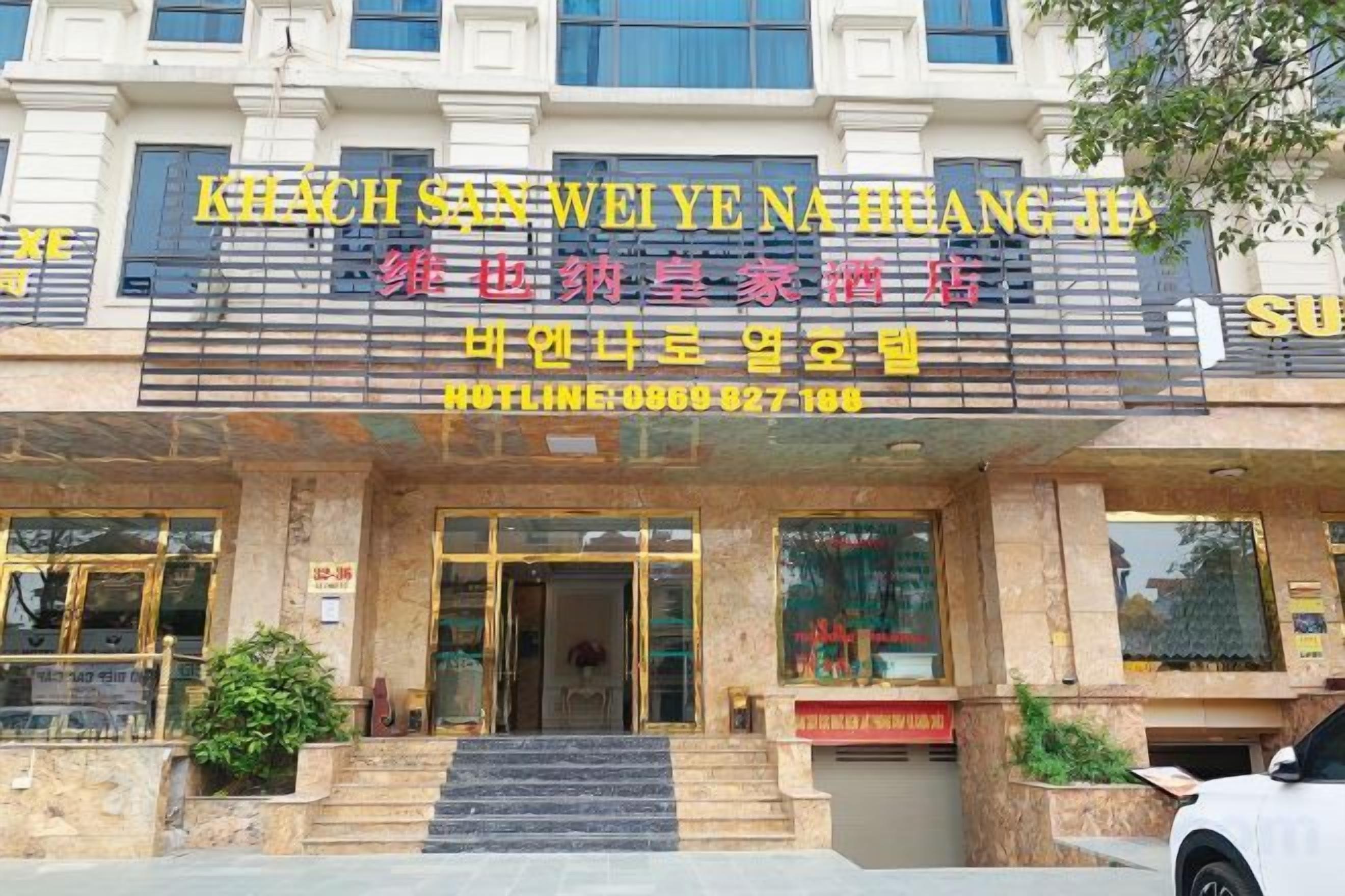 A hotel entrance with a sign in Chinese characters, a staircase leading up to the entrance, and a car parked in front.