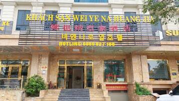 A hotel entrance with a sign in Chinese characters, a staircase leading up to the entrance, and a car parked in front.