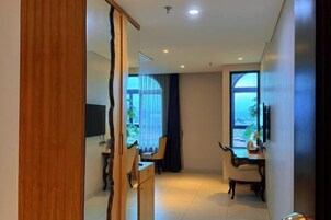 Habitación de hotel moderna con un armario de madera, un escritorio, una silla y un ventanal con vistas.