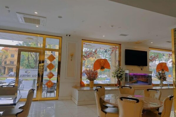 A hotel lobby with a reception desk, seating area, and large windows. - Vienna Royal Hotel Bac Ninh (Bac Ninh)