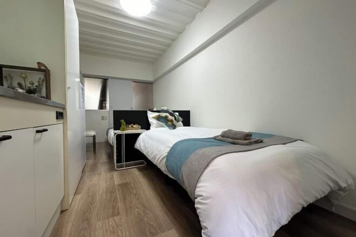 A small, modern bedroom with a bed, bedside table, and a mirror.