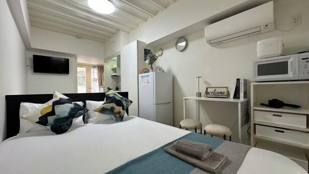 A hotel room with a bed, a desk, a microwave, and an air conditioning unit. - 3 Guests Kitchen & Washer 7-min Walk to Waseda University (Tokyo)