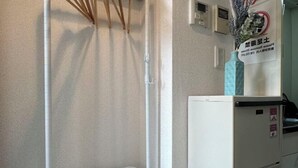 A hotel room with a white wall, a white radiator, a white basket, a white cabinet with a green sign, and a decorative vase. - 3 Guests Kitchen & Washer 7-min Walk to Waseda University (Tokyo)