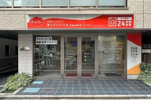 A storefront with a red awning, glass doors, and a sign indicating 24-hour service.