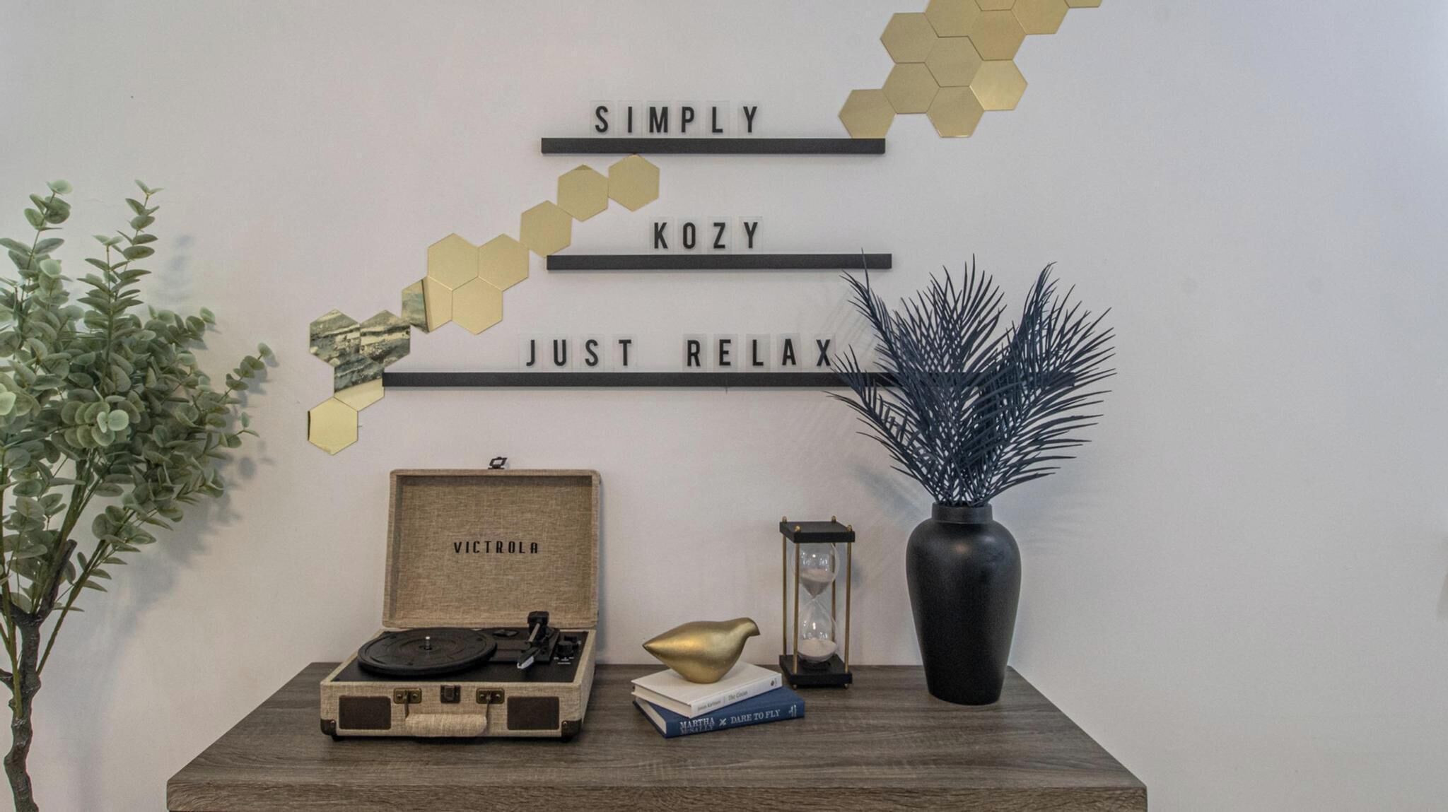 Una pared con diseños hexagonales decorativos y un letrero que dice "SIMPLY KOZY JUST RELAX".