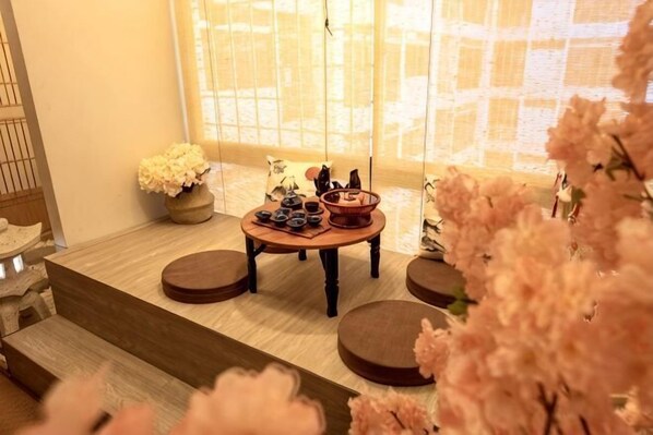 A room with a tatami mat floor, a low wooden table with decorative items, and a window with a view.