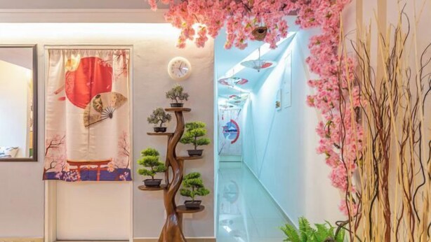 A reception area with a traditional Japanese aesthetic, including a wooden tree-shaped shelf with potted plants, a decorative fan, and a clock on the wall. - Fahrenheit88-Ancient Loft House ( Japan Theme ) (Kuala Lumpur)