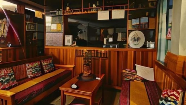 Una stanza accogliente, con rivestimento in legno, un divano, un tavolino e mensole piene di libri e oggetti decorativi.